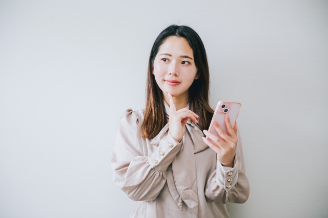 スマホを手にして考える女性